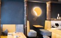 Minimalistische Restaurant-Einrichtung mit warmen Holztönen und dunklen Farben. Gezielte Lichtinszenierung für ein gemütliches, einladendes Ambiente